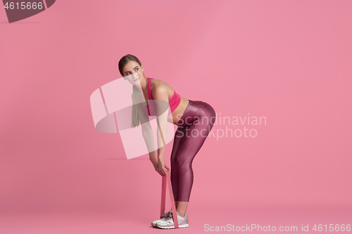 Image of Beautiful young female athlete practicing on pink studio background, monochrome portrait