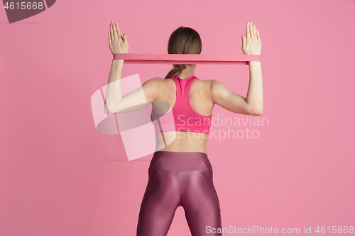 Image of Beautiful young female athlete practicing on pink studio background, monochrome portrait