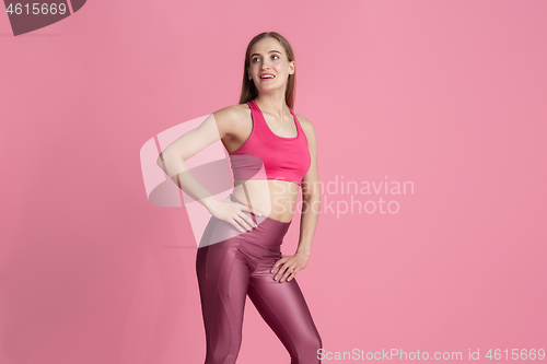 Image of Beautiful young female athlete practicing on pink studio background, monochrome portrait