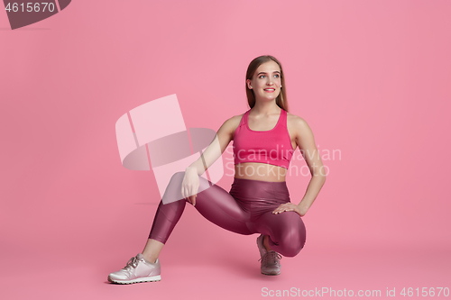 Image of Beautiful young female athlete practicing on pink studio background, monochrome portrait