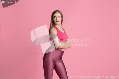 Image of Beautiful young female athlete practicing on pink studio background, monochrome portrait