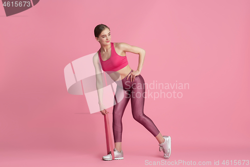 Image of Beautiful young female athlete practicing on pink studio background, monochrome portrait