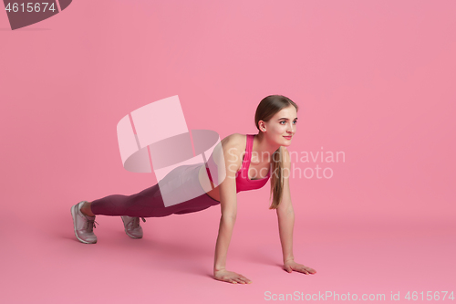 Image of Beautiful young female athlete practicing on pink studio background, monochrome portrait