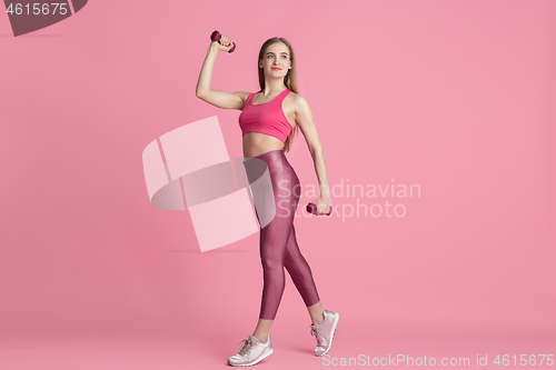 Image of Beautiful young female athlete practicing on pink studio background, monochrome portrait