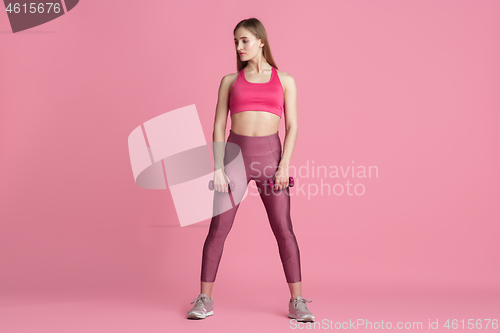 Image of Beautiful young female athlete practicing on pink studio background, monochrome portrait