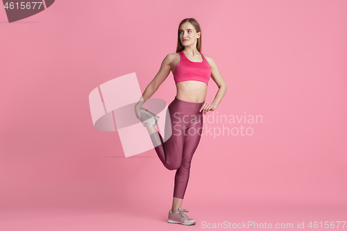 Image of Beautiful young female athlete practicing on pink studio background, monochrome portrait