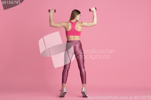 Image of Beautiful young female athlete practicing on pink studio background, monochrome portrait