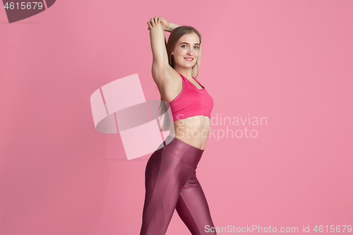 Image of Beautiful young female athlete practicing on pink studio background, monochrome portrait