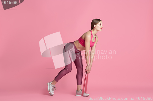 Image of Beautiful young female athlete practicing on pink studio background, monochrome portrait