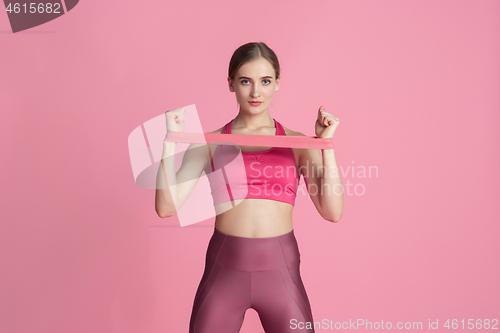 Image of Beautiful young female athlete practicing on pink studio background, monochrome portrait