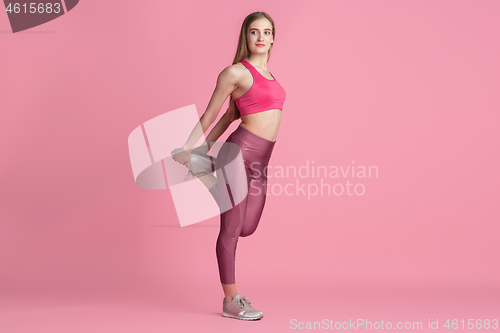 Image of Beautiful young female athlete practicing on pink studio background, monochrome portrait