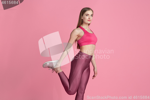 Image of Beautiful young female athlete practicing on pink studio background, monochrome portrait