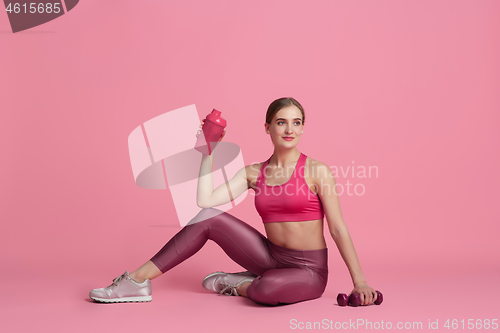 Image of Beautiful young female athlete practicing on pink studio background, monochrome portrait