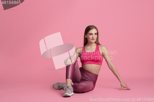 Image of Beautiful young female athlete practicing on pink studio background, monochrome portrait