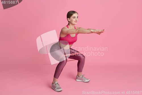 Image of Beautiful young female athlete practicing on pink studio background, monochrome portrait