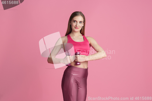 Image of Beautiful young female athlete practicing on pink studio background, monochrome portrait