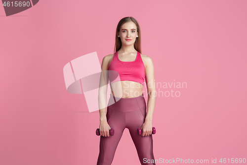 Image of Beautiful young female athlete practicing on pink studio background, monochrome portrait