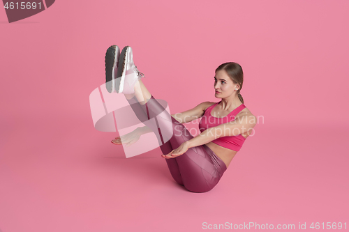 Image of Beautiful young female athlete practicing on pink studio background, monochrome portrait