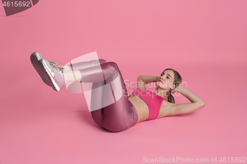 Image of Beautiful young female athlete practicing on pink studio background, monochrome portrait