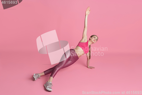 Image of Beautiful young female athlete practicing on pink studio background, monochrome portrait