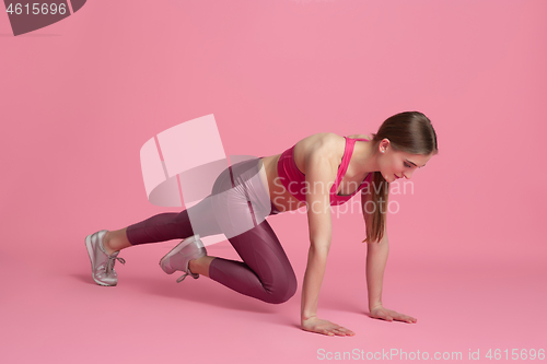 Image of Beautiful young female athlete practicing on pink studio background, monochrome portrait