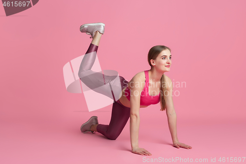 Image of Beautiful young female athlete practicing on pink studio background, monochrome portrait