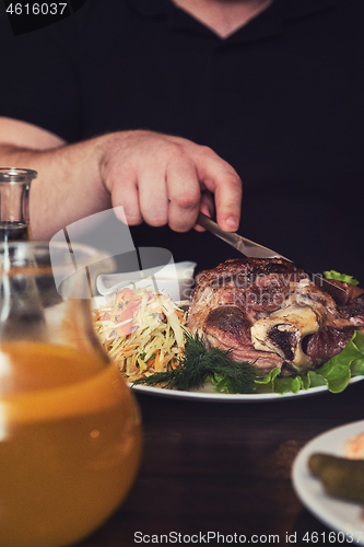 Image of Man eats tasty dish of pork shank