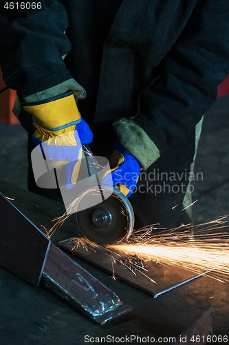 Image of worker cutting metal with grinder