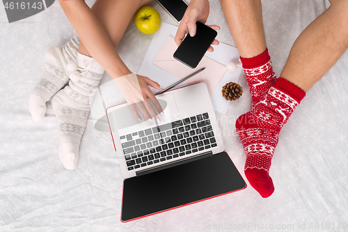 Image of caucasian couple at home using internet technology LLaptop and phone for people sitting on the floor