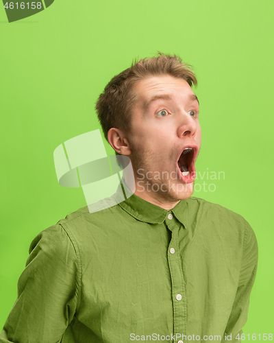 Image of The man screaming with open mouth isolated on green background, concept face emotion