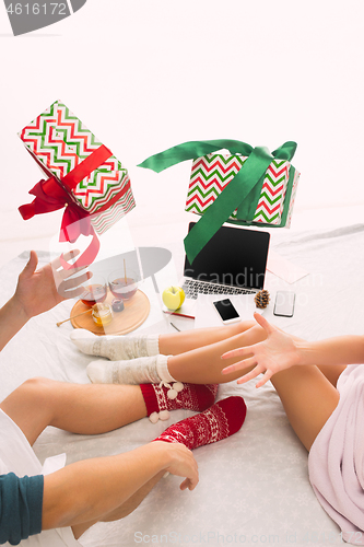 Image of caucasian couple at home with gift. Laptop and phone for people sitting on the floor