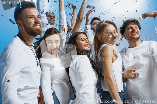 Image of Group of cheerful joyful young people standing and celebrating together over blue background