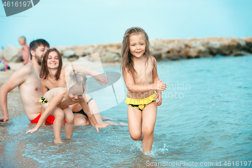 Image of Happy family enjoying walk on the beach