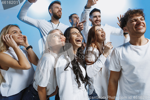 Image of Group of cheerful joyful young people standing and celebrating together over blue background