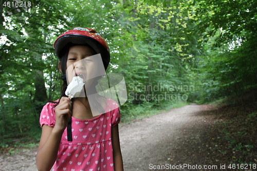 Image of Portrait of a young cute girl looking at the camera eating an ic