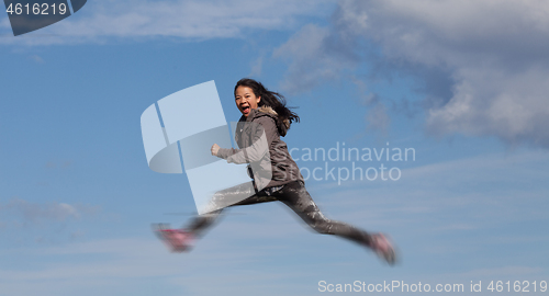 Image of Cute girl running jumping at the on a field in the summer