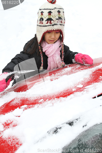 Image of Portrait of a young cute girl looking at the camera romoving sno