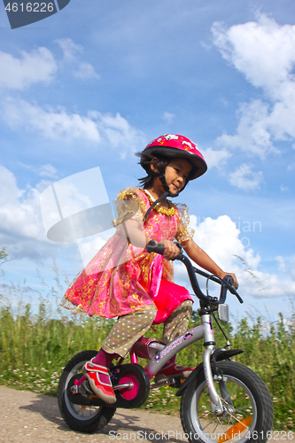 Image of Cute girl cycling with a princess outfit