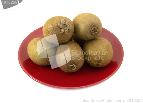 Image of Whole kiwifruits with hairy skins piled on a red plate