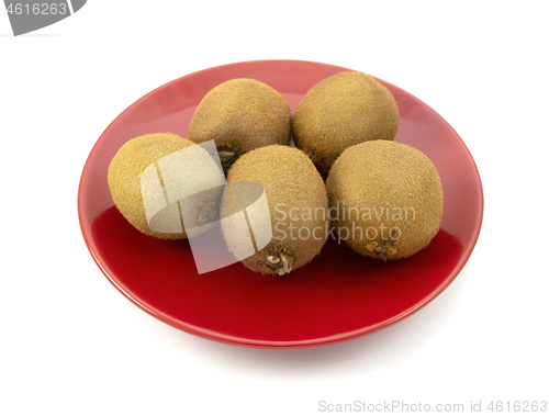 Image of Five fresh whole kiwi fruits on a red plate