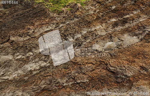 Image of A cut of soil with rocks and red soil