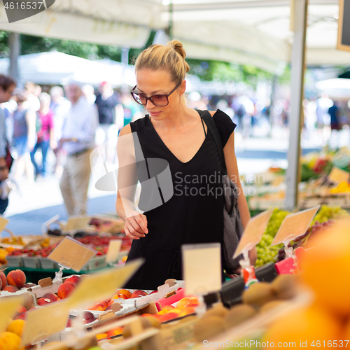 Image of Woman buying fruits and vegetables at local food market. Market stall with variety of organic vegetable
