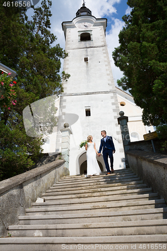 Image of The Kiss. Bride and groom kisses tenderly on a staircase in front of a small local church.