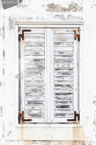 Image of White weathered rusted wooden window shutters.