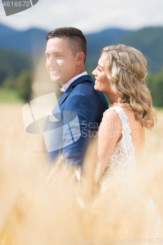 Image of Newlyweds hugging tenderly in wheat field somewhere in Slovenian countryside. Caucasian happy romantic young couple celebrating their marriage