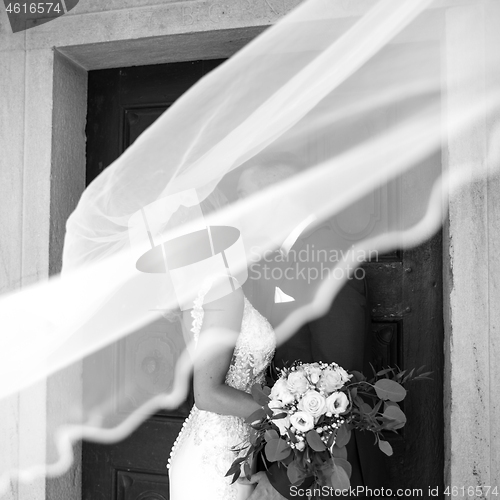 Image of The kiss. Bride and groom kisses tenderly in the shadow of a flying veil. Artistic black and white wedding photo.