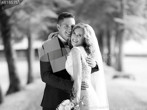 Image of Bride and groom hugging tenderly posing during photo shooting in park.