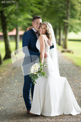 Image of Bride and groom hugging tenderly posing during photo shooting in park.