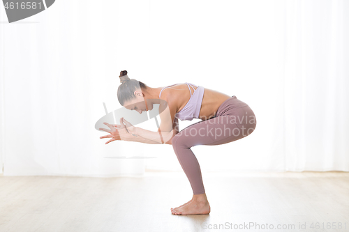 Image of Portrait of gorgeous active sporty young woman practicing yoga in studio. Beautiful girl practice Garurasana, eagle yoga pose. Healthy active lifestyle, working out indoors in gym