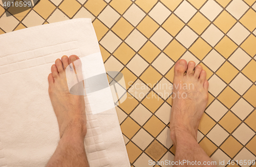 Image of After taking a shower; Male feet on a vintage bathroom floor